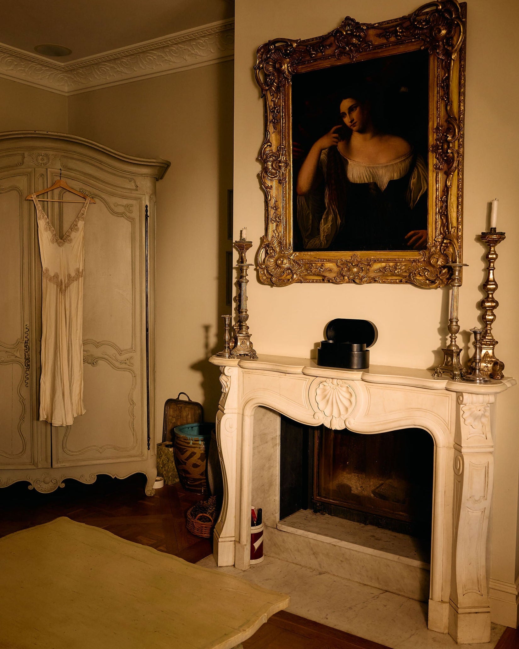 Vintage room with a fireplace, mirror, and hanging dress.