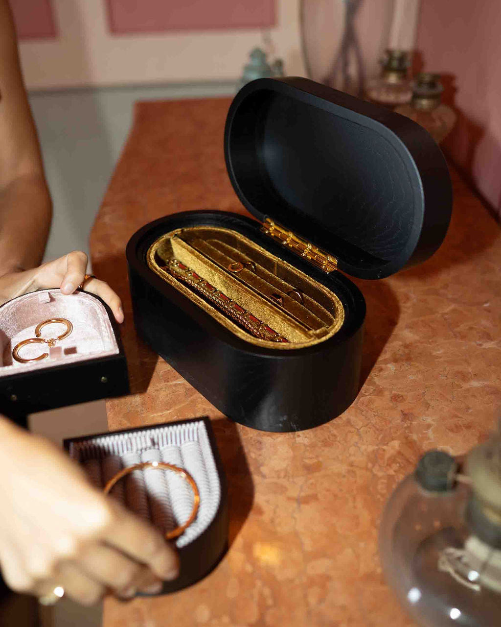 Open black jewelry box with gold rings on a wooden surface.