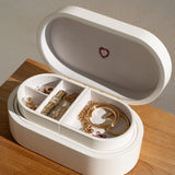 White jewelry box with gold jewelry on a wooden surface