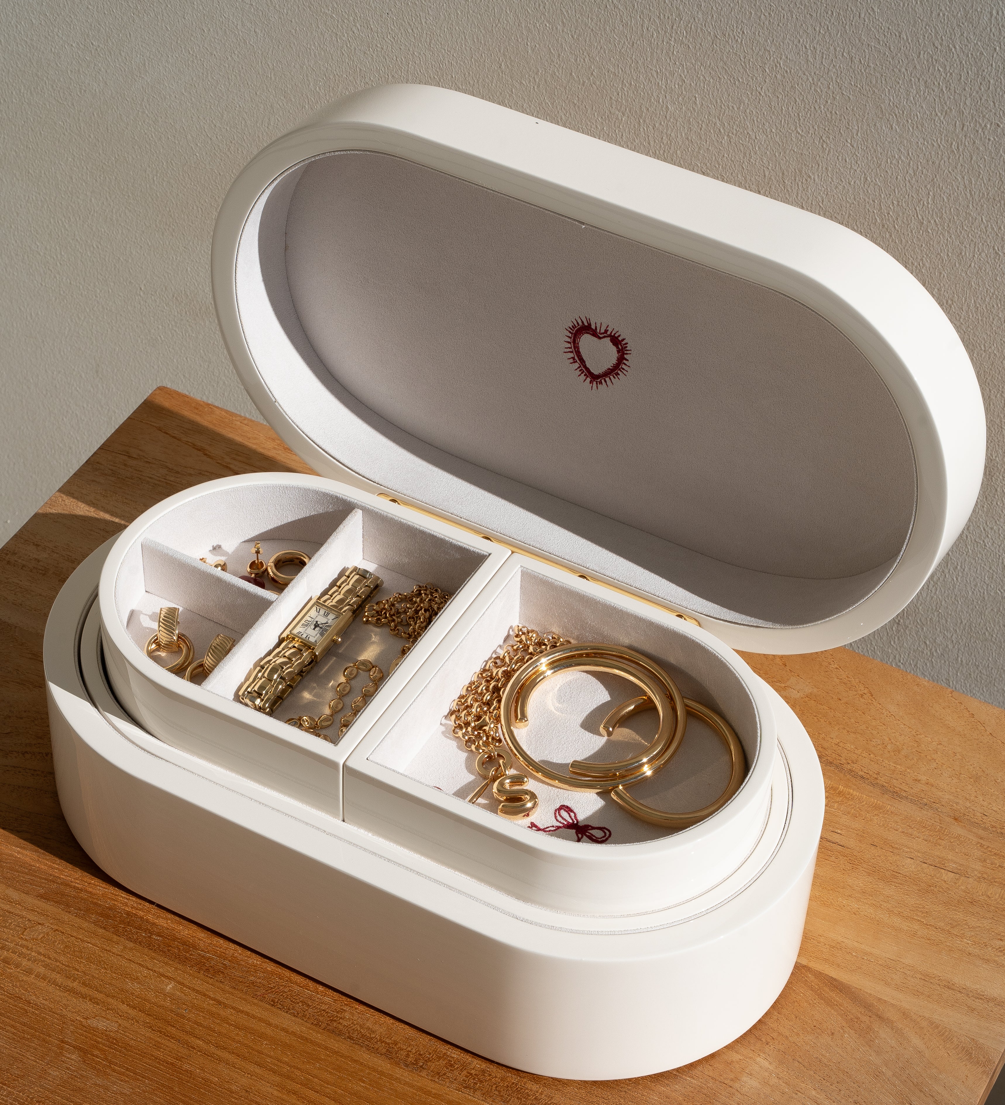 White jewelry box with gold jewelry on a wooden surface