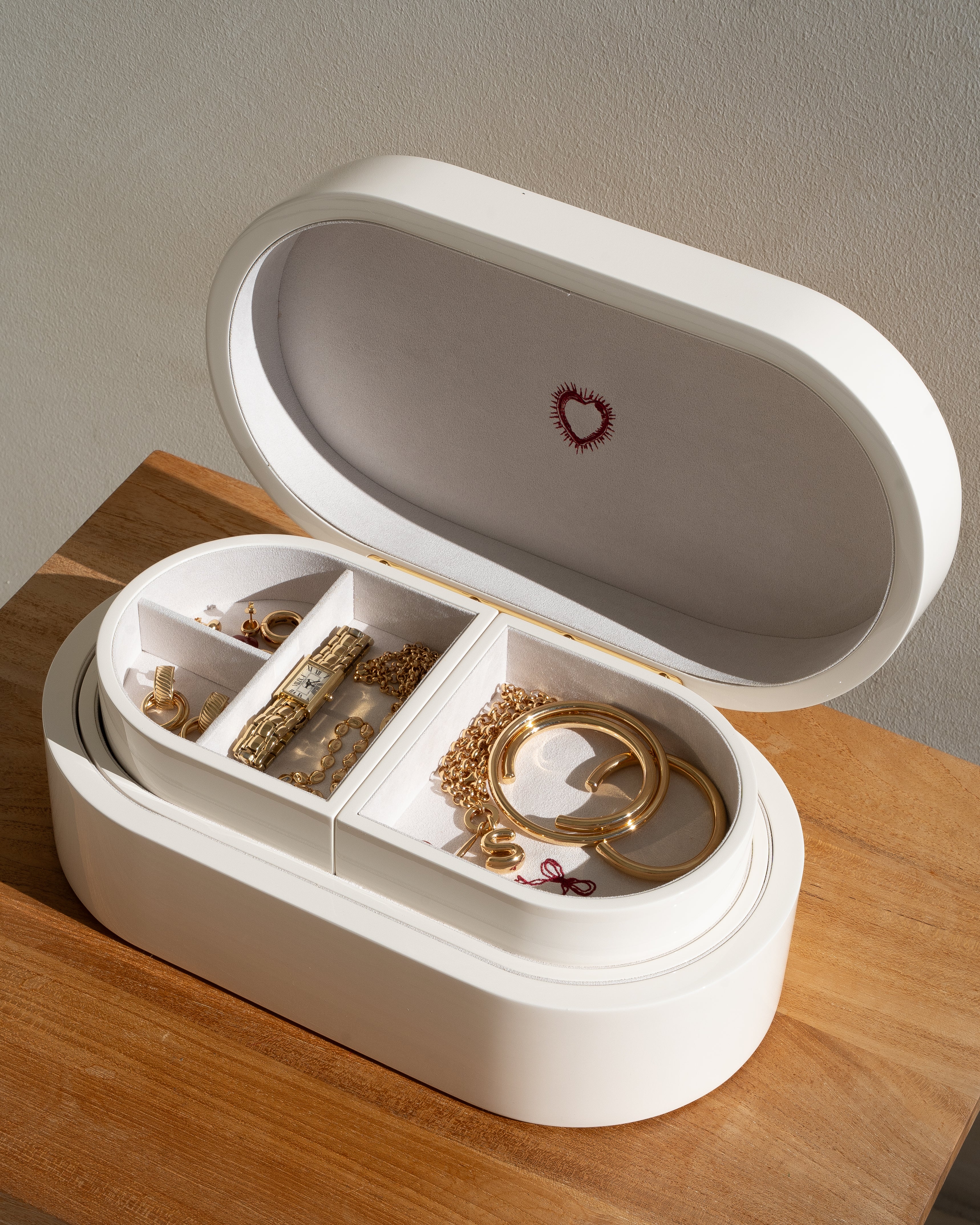 White jewelry box with gold jewelry on a wooden surface