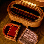 Wooden jewelry box with two smaller compartments on a patterned surface