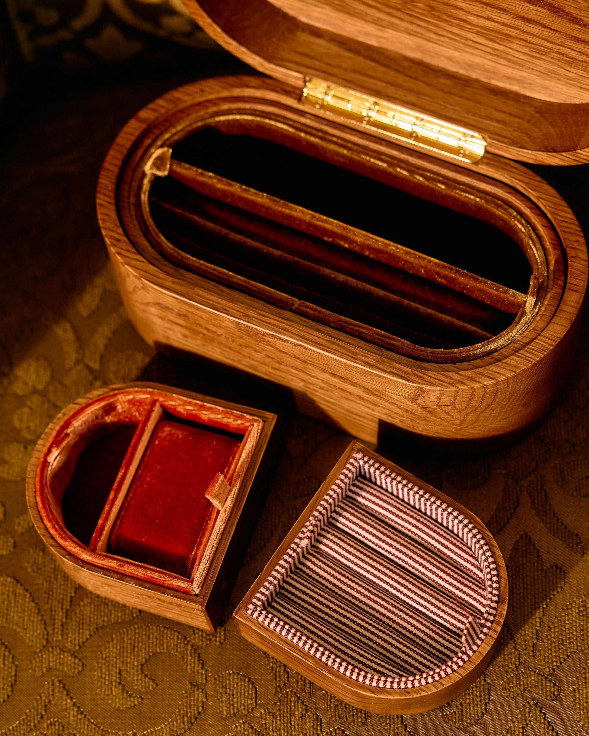 Wooden jewelry box with two smaller compartments on a patterned surface