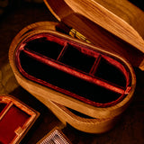 Wooden jewelry box with red interior on a patterned surface