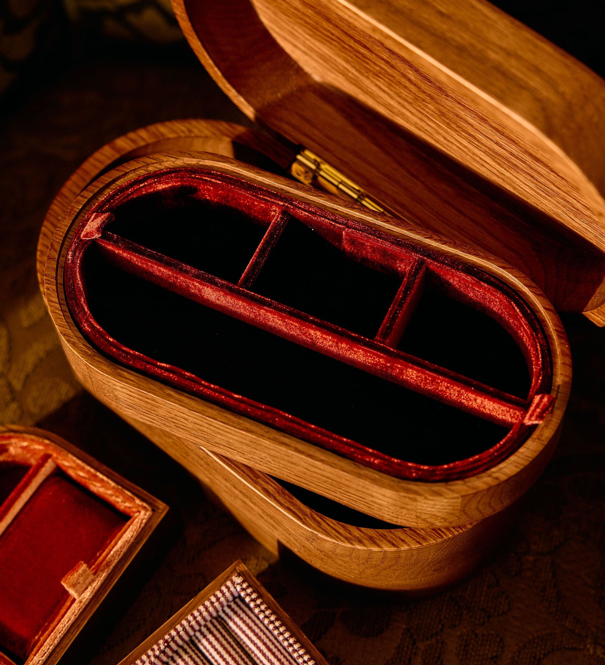Wooden jewelry box with red interior on a patterned surface