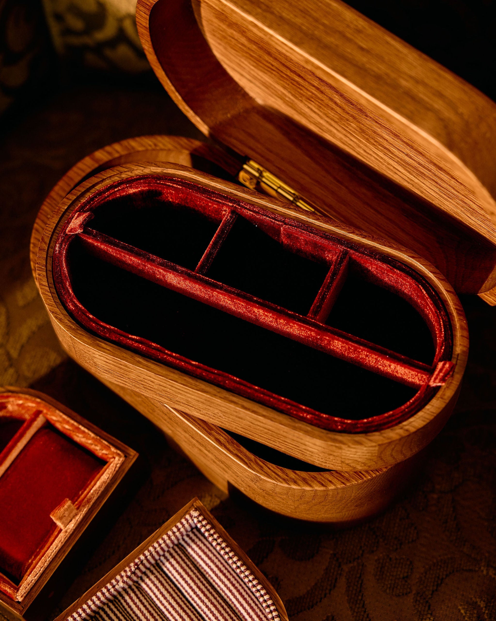 Wooden jewelry box with red interior on a patterned surface