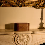 Decorative wooden box on a ornate wooden surface with a gold-framed mirror in the background.