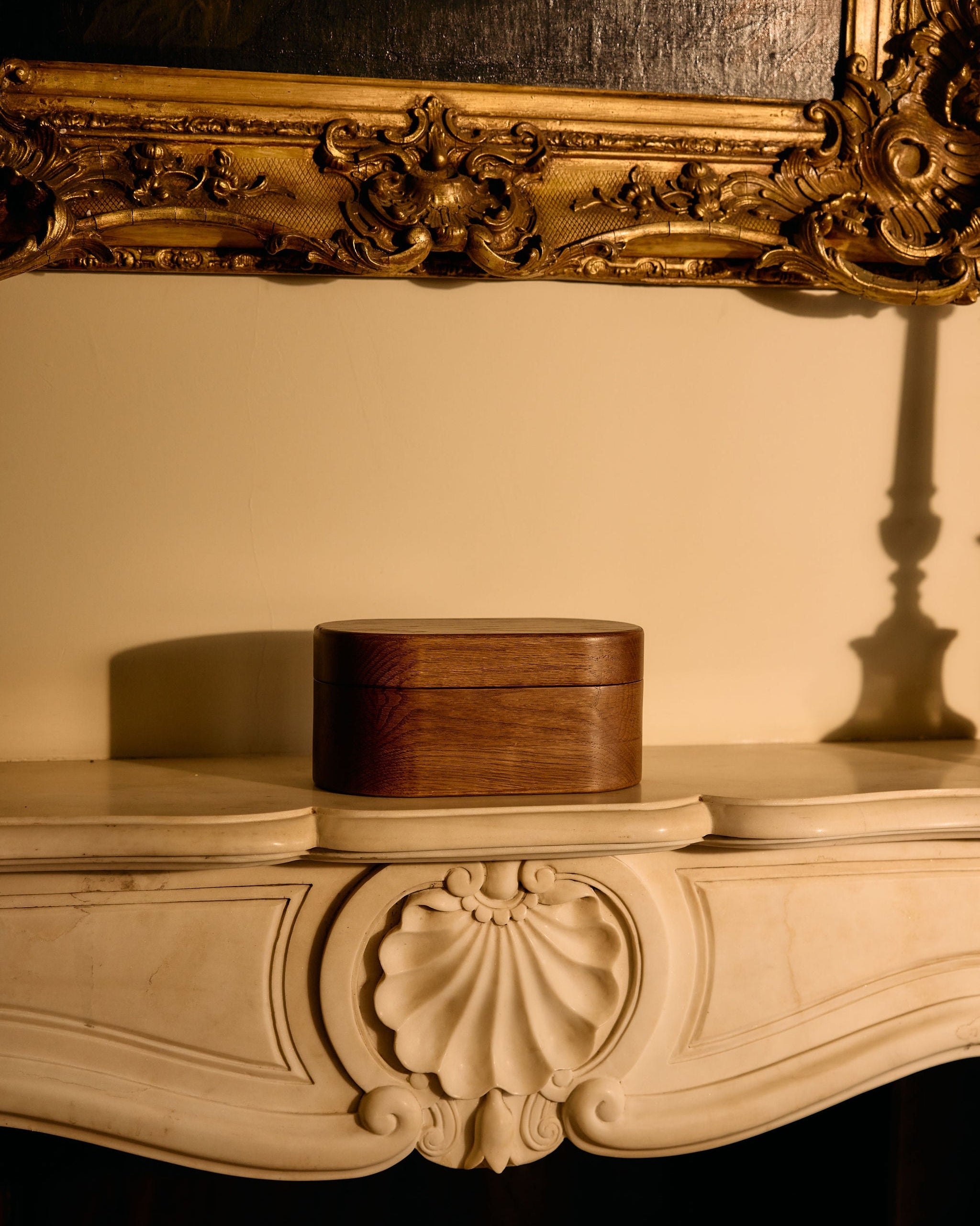 Decorative wooden box on a ornate wooden surface with a gold-framed mirror in the background.