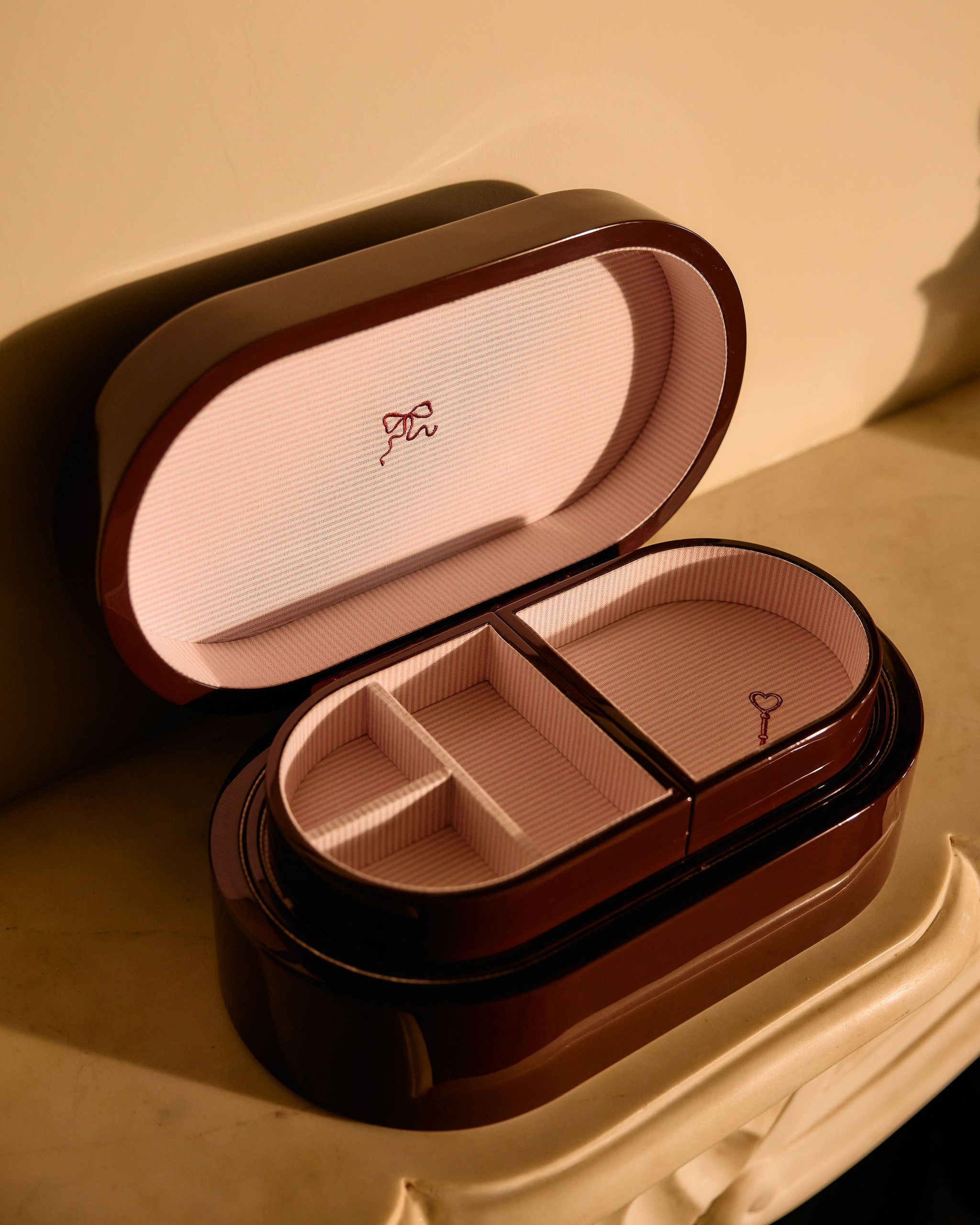 Open jewelry box with a pink interior on a beige background