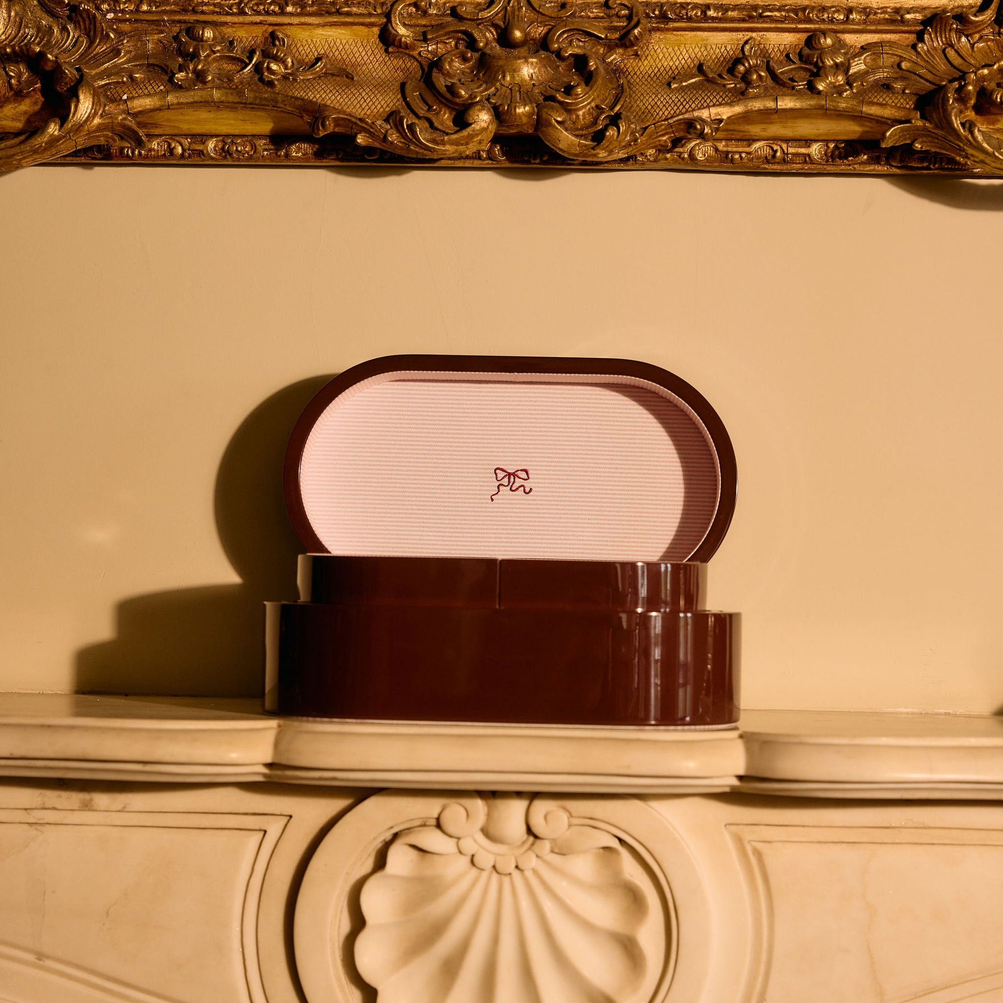Decorative jewelry box with a gold frame and intricate design on a reflective surface.