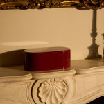 Decorative red box on an ornate surface with a gold-framed mirror in the background.