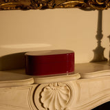 Decorative red box on an ornate surface with a gold-framed mirror in the background.