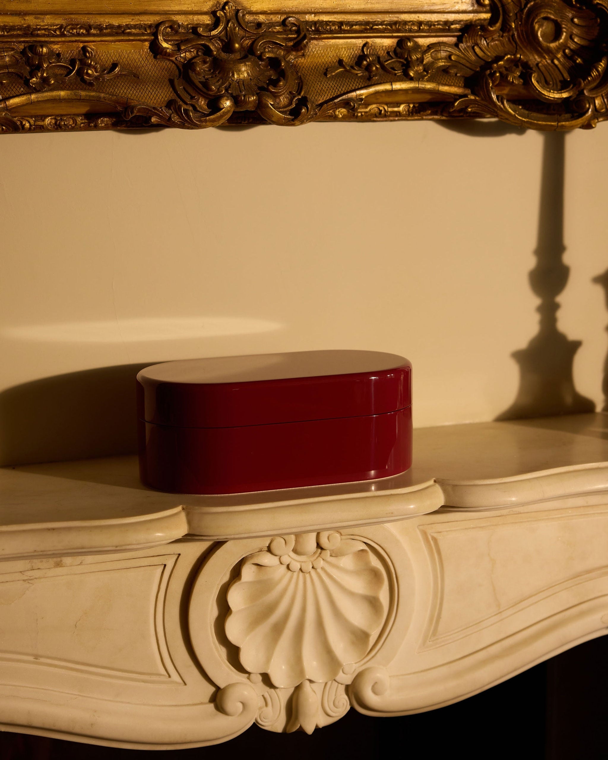 Decorative red box on an ornate surface with a gold-framed mirror in the background.