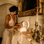 Woman in a white dress interacting with a toilet in an ornate room.