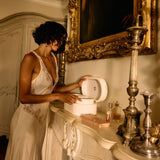 Woman in a white dress interacting with a toilet in an ornate room.