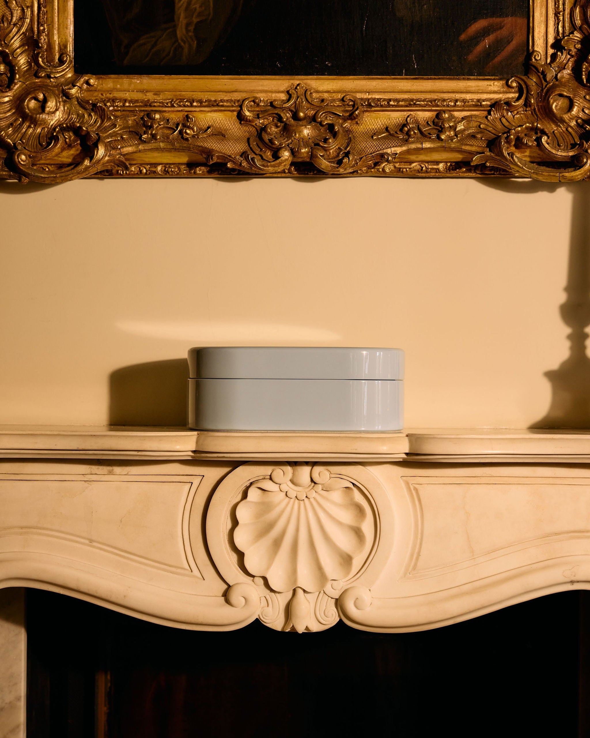 Jewellery box on a mantelpiece with an ornate gold frame above
