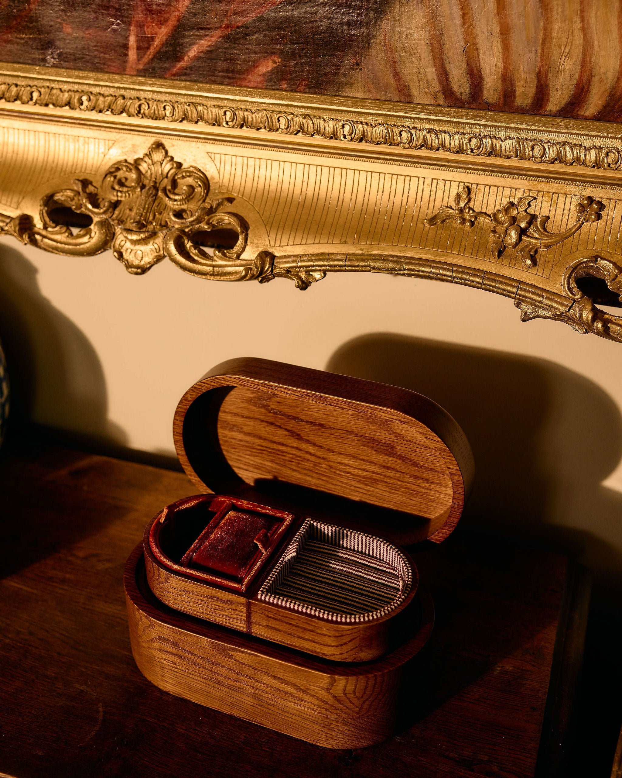 Wooden jewelry box with cards on a wooden surface, ornate gold frame in the background