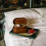 Wooden box on a tray with a teacup on a bed with decorative headboard