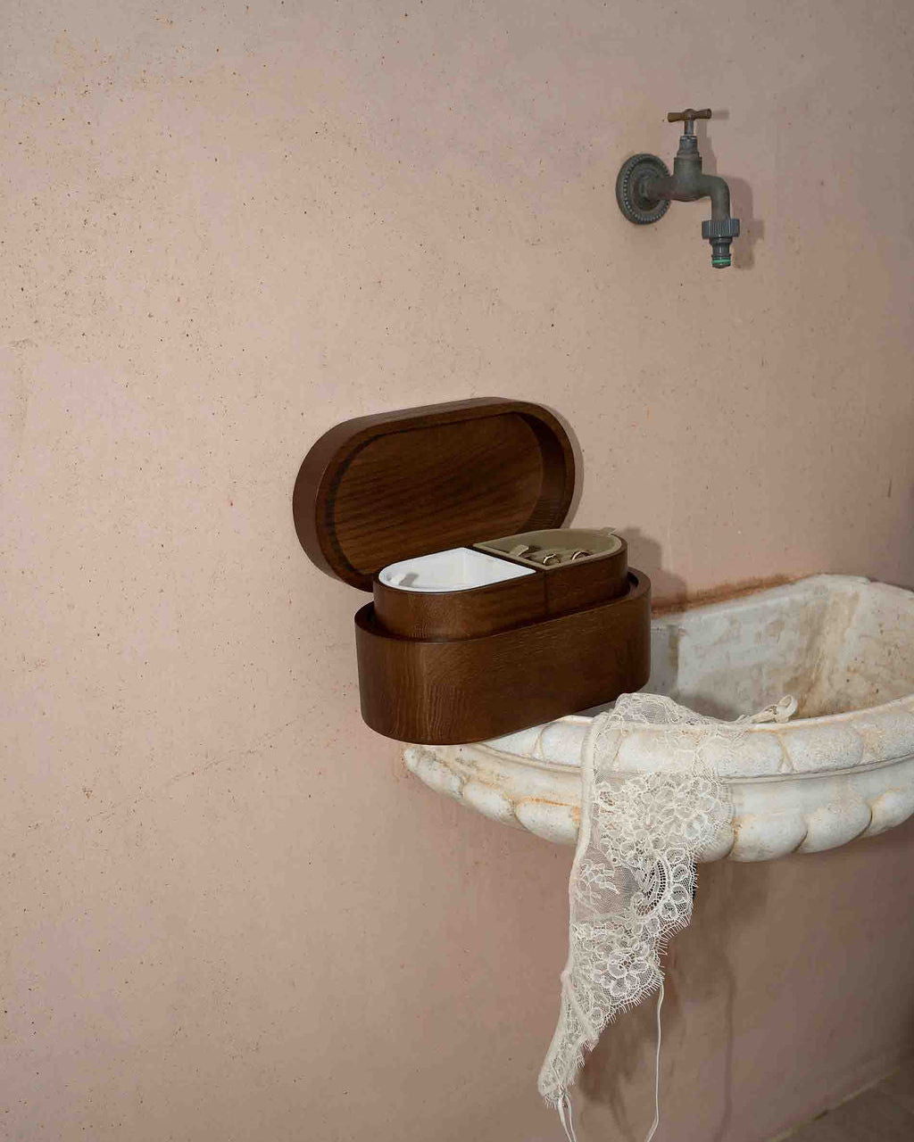 Wooden box on a vintage-style sink with a faucet against a beige wall.