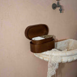 Wooden box on a vintage-style sink with a faucet against a beige wall.