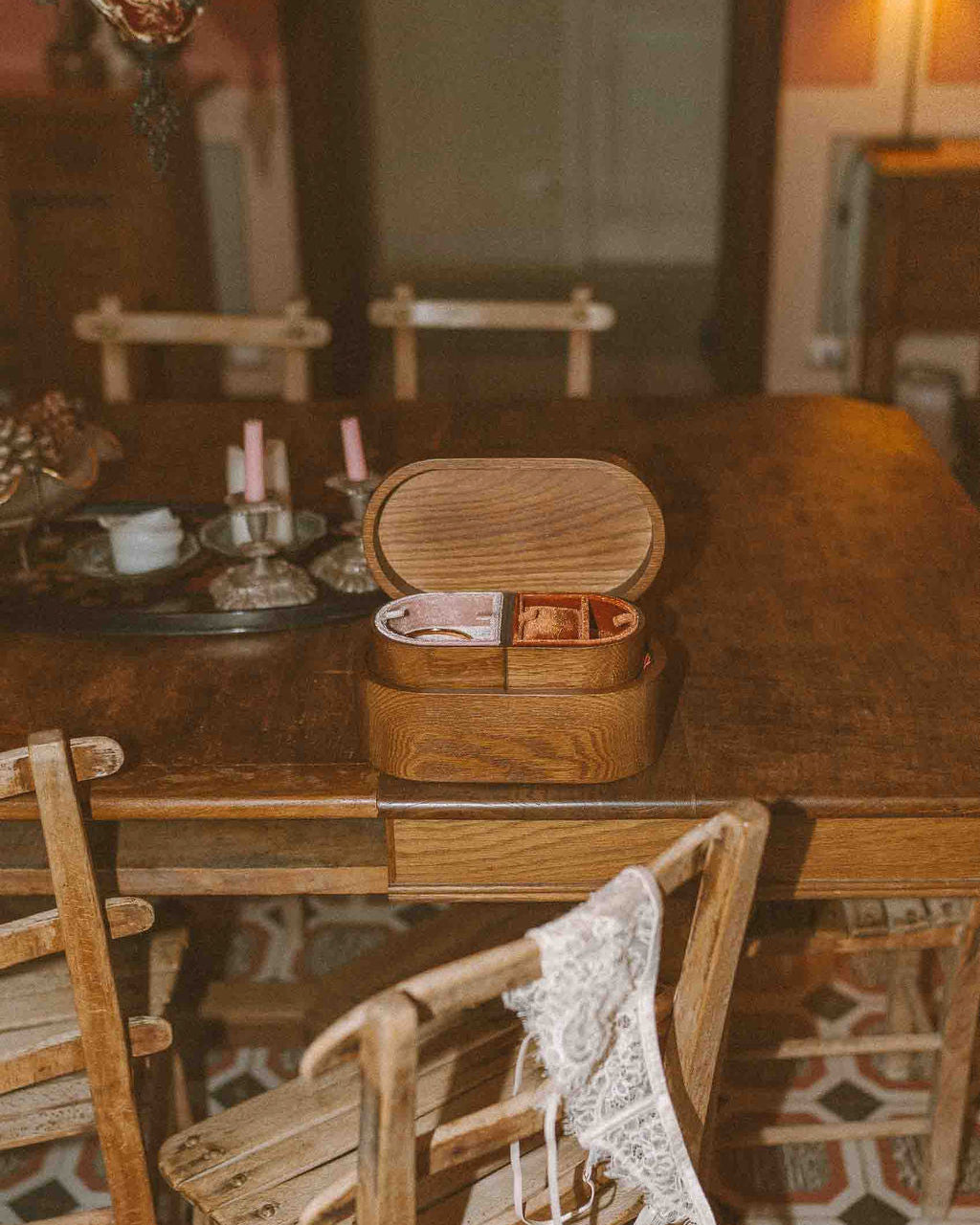 Wooden table with a box on top in a room with patterned floor and chairs.