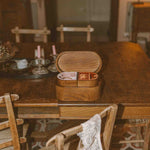 Wooden table with a box on top in a room with patterned floor and chairs.