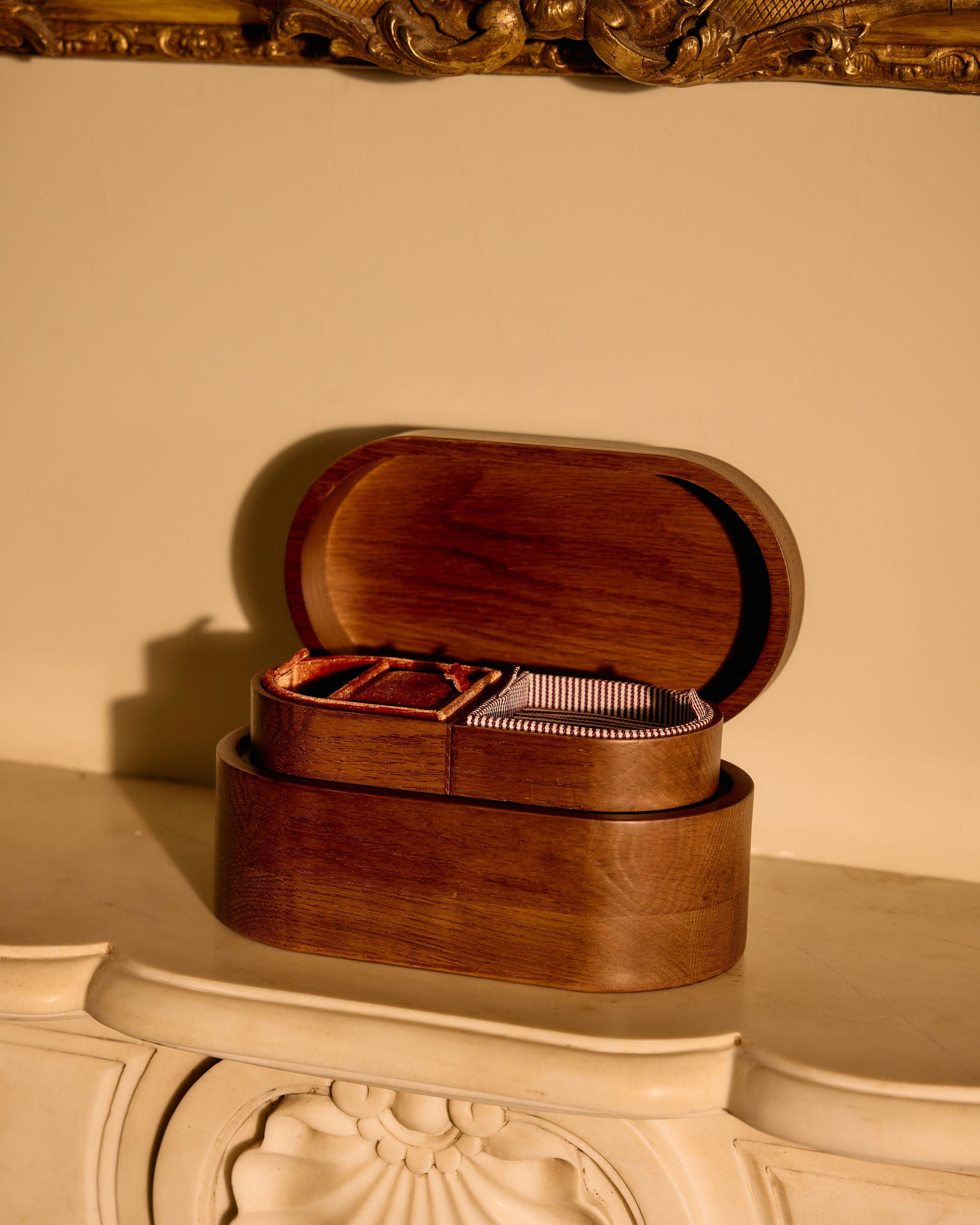 Wooden jewelry box on a decorative surface with a beige wall in the background